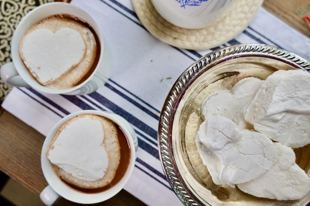 hot chocolate with homemade marshmallows with a silver dish of heart shaped marshmallows