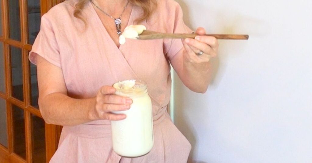 Women is holding a spoon with thick homemade yogurt on it
