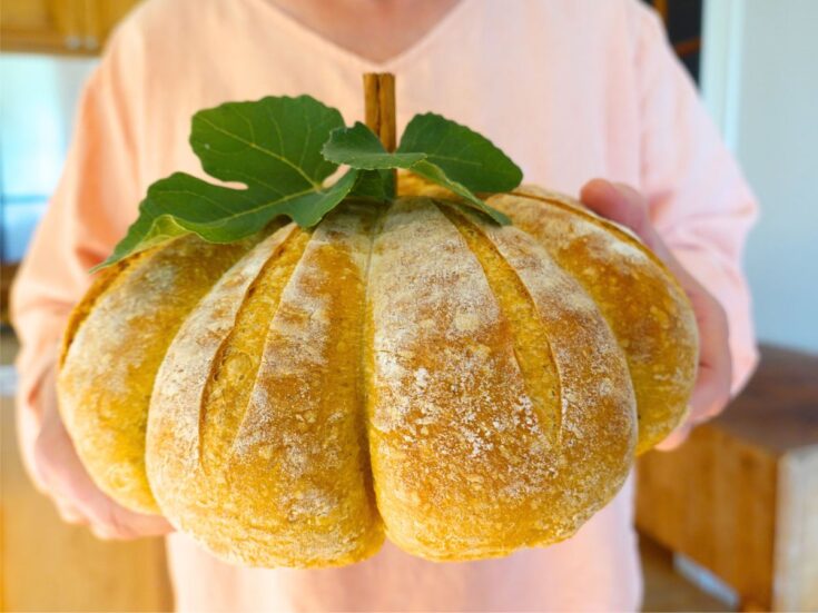woman holding sourdough pumpkin shaped bread in front